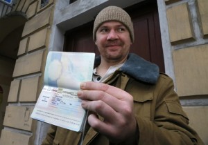 Greenpeace International activist Anthony Perrett of the United Kingdom shows to journalists his passport with permission to leave Russia, near the Federal Migration Service in St. Petersburg, Russia, Thursday, Dec. 26, 2013. Russian investigators have dropped charges against all but one of the 30 crew of a Greenpeace ship, who were accused of hooliganism following a protest outside a Russian oil rig in the Arctic. (AP Photo/Dmitry Lovetsky)