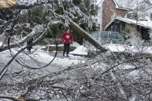 A resident surveys the damage after power lines came down across the street in Toronto's east end on Sunday, December 22, 2013. THE CANADIAN PRESS/Chris Young 